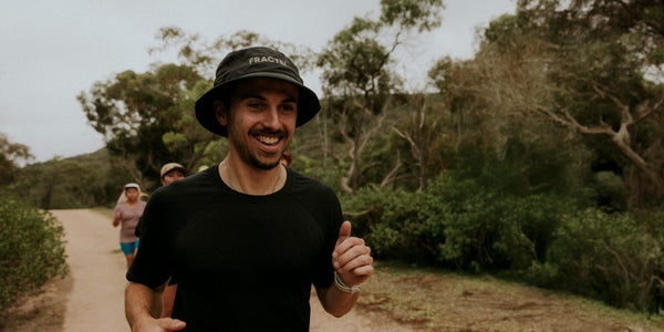 Smiling runner in a black Fractel core bucket hat on a bush trail