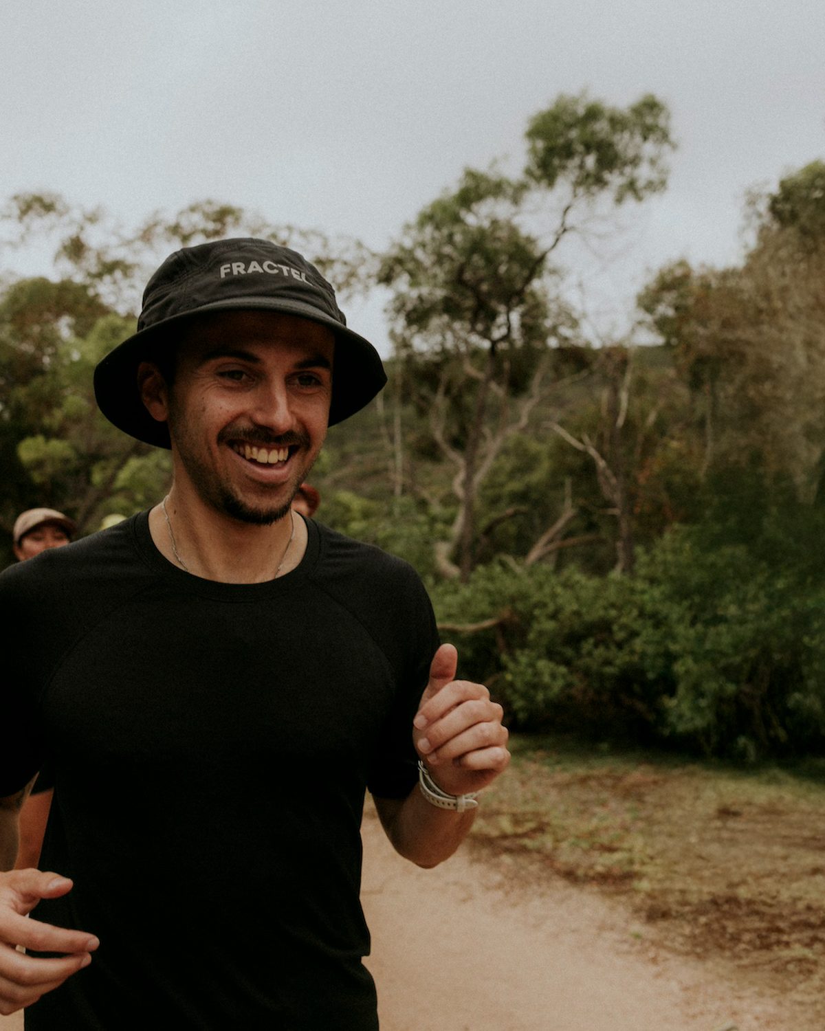 Runner wearing a black core bucket hat from Fractel on a bush trail