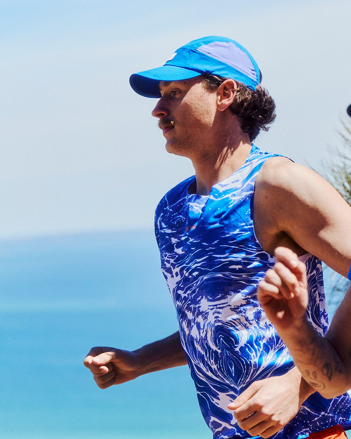 Velocity running collection: blue patterned singlet and tee on a coastal run
